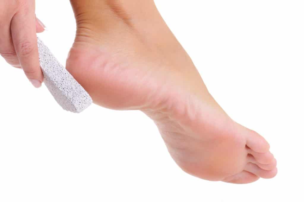 female scrubbing foot by pumice